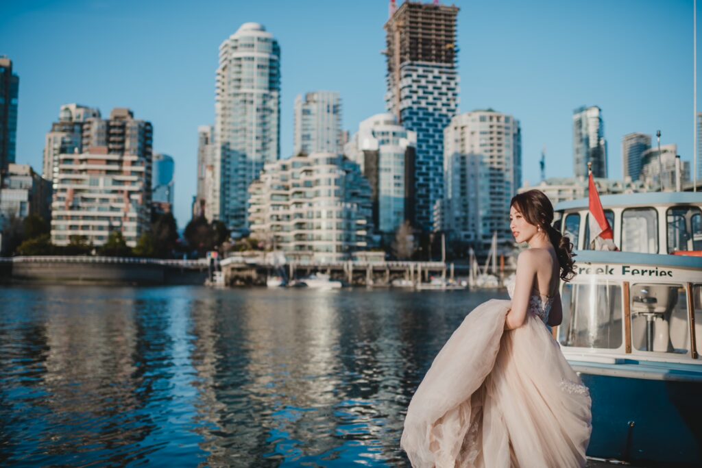 穿著米色婚紗的新娘站在港邊，背景為現代高樓與水面倒影的城市景色